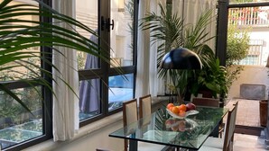 Un invernadero con una mesa de vidrio, sillas y plantas en macetas.