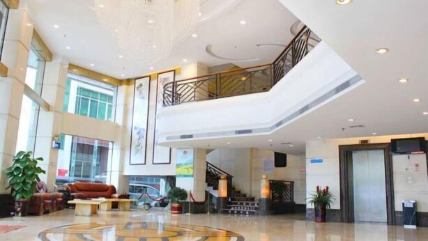 Eine geräumige Lobby mit einer zentralen Sitzgelegenheit, einer Treppe und einer großen Chandelier.