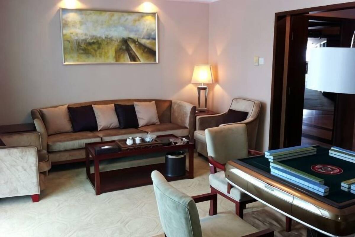 Een woonkamer met een bank, fauteuils, een salontafel en een boekenkast.