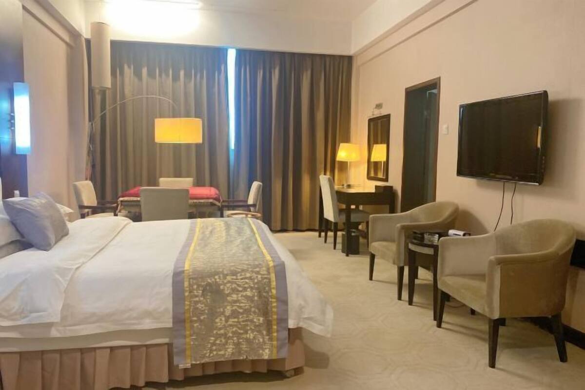 Een hotelkamer met een bed, een bureau, een stoel, een televisie en een lamp.