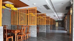 Eine großzügige Lobby mit einer langen Rezeption, Holzstühlen und einem Fliesenboden.