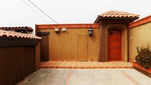 A gated entrance with a brown door, a small light fixture above it, and a tiled roof. - Beachfront Studio Wonderful  Ocean Views, private access to beach (San Antonio del Mar)