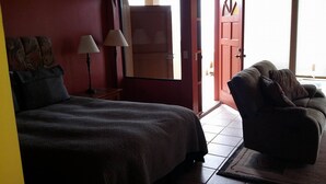 A bedroom with a bed, a chair, a lamp, and a door leading to another room. - Beachfront Studio Wonderful  Ocean Views, private access to beach (San Antonio del Mar)