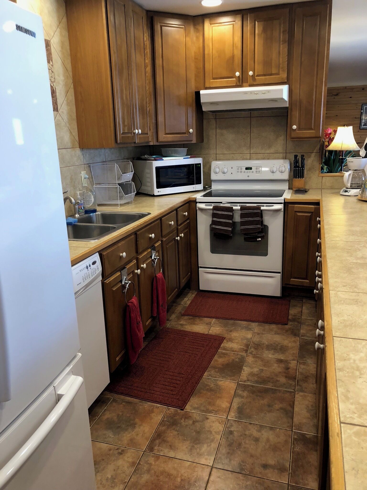 A kitchen with wooden cabinets, a microwave, stove, dishwasher, and a refrigerator.