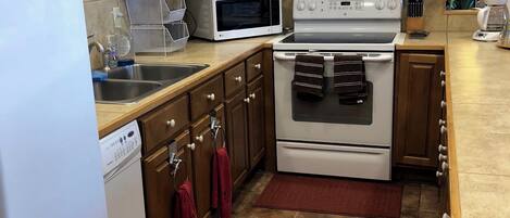 A kitchen with wooden cabinets, a microwave, stove, dishwasher, and a refrigerator.