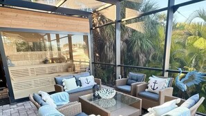 Un espacio de estar al aire libre cubierto con mobiliario de mimbre, cojines y una cesta tejida de toallas.