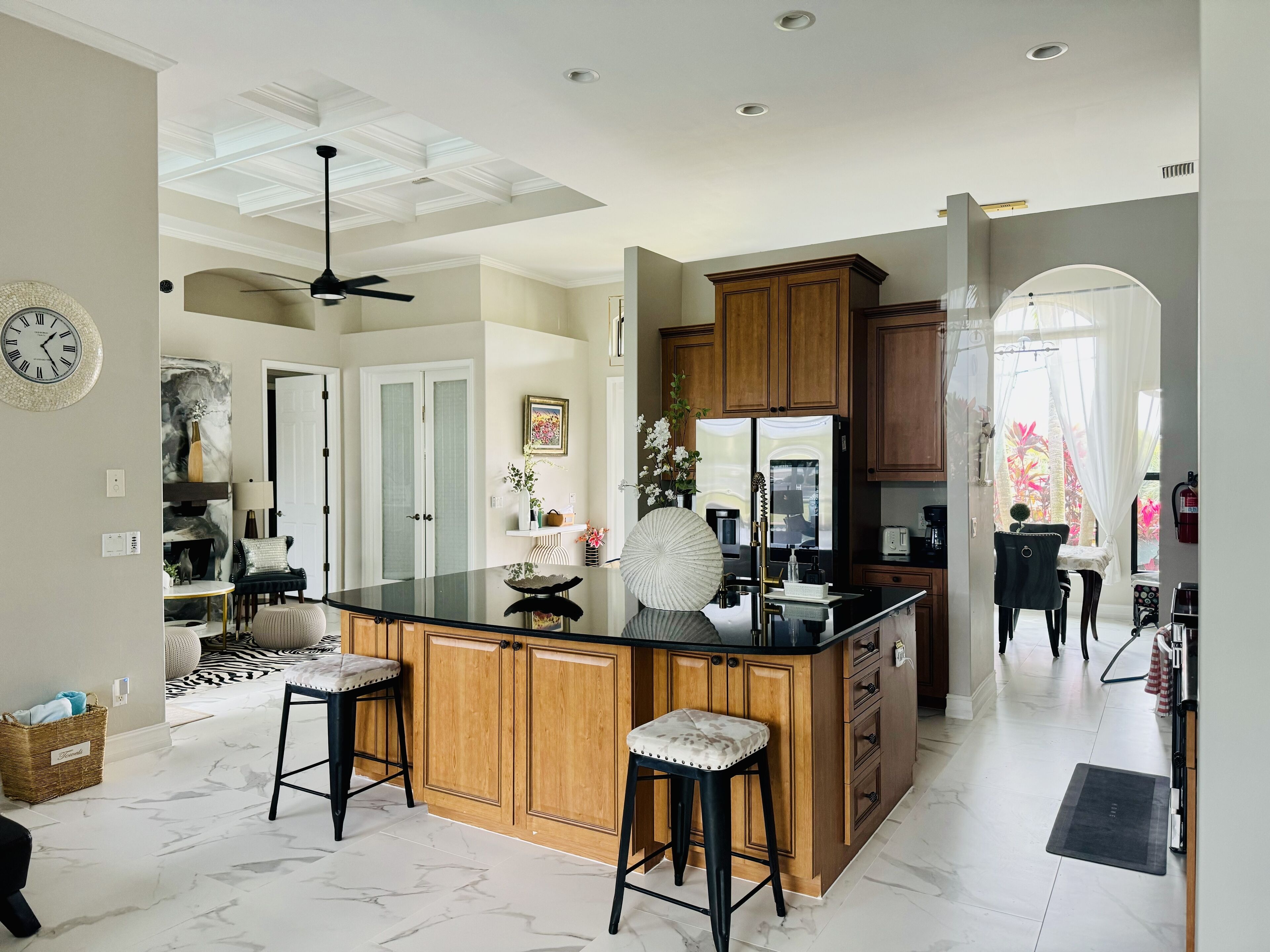 Una cocina moderna con una isla central, armarios de madera y piso de mármol.