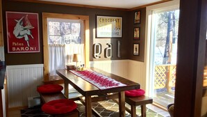 Un comedor con una mesa de madera, cojines rojos y una alfombra estampada.