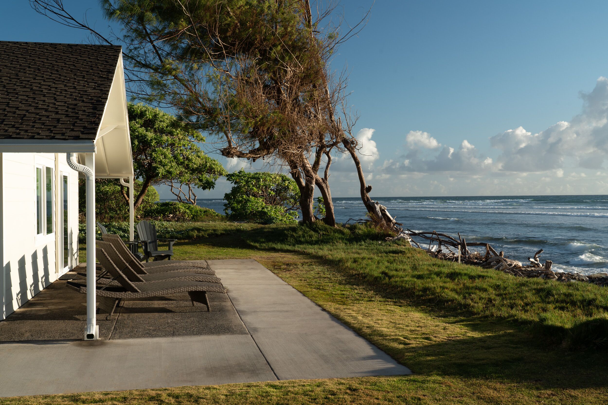 A coastal building with a concrete pathway, outdoor seating, and a view of the ocean.