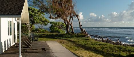 A coastal building with a concrete pathway, outdoor seating, and a view of the ocean.