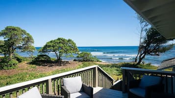A wooden deck with wicker furniture overlooking the ocean.