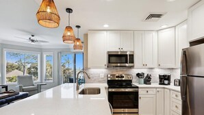 Una cocina moderna con armarios blancos, electrodomésticos de acero inoxidable y una isla grande con lavamanos.