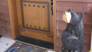 Une porte en bois avec un loquet métallique et une pancarte de bienvenue accrochée au mur.