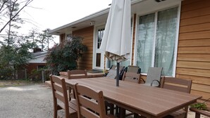 A wooden deck with a table and chairs, a covered umbrella, and a house in the background. - Mid Century Modern Retreat in North Augusta (North Augusta)
