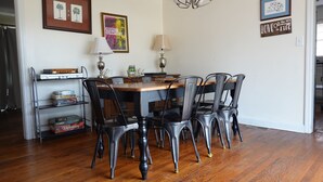 A dining area with a wooden table and black chairs, a chandelier, and framed artwork on the walls. - Mid Century Modern Retreat in North Augusta (North Augusta)