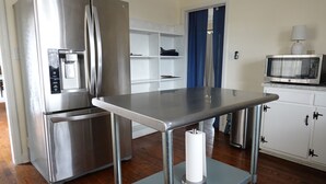 A kitchen with a stainless steel refrigerator, a microwave, and a table with a roll of paper towels. - Mid Century Modern Retreat in North Augusta (North Augusta)