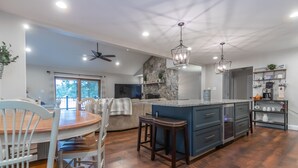 A spacious kitchen with a central island, wooden flooring, and modern lighting fixtures.