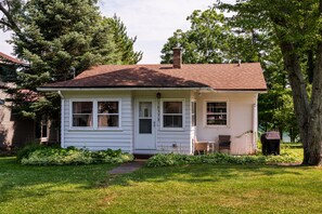 A single-story house with a red roof, white siding, and a front porch.