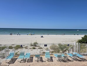 A beach with lounge chairs and a fence.