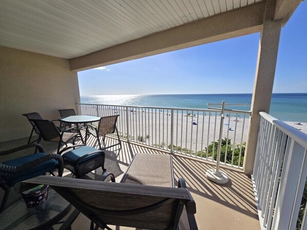 A covered outdoor area with a view of the beach, featuring a table and chairs.