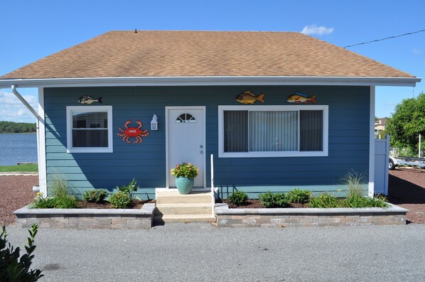 A house with a blue exterior, a brown roof, and a small front porch with steps.