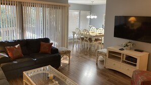 A living room with a sofa, a glass coffee table, a TV, and a dining area with chairs and a table. - Newly Updated, Near Harbour Town 1st Floor 2 Bedroom 2Bath  Villa  (Hilton Head Island)