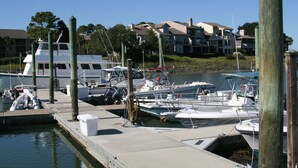 A marina with several boats docked, a dock with a boat ramp, and a building with a balcony in the background. - Newly Updated, Near Harbour Town 1st Floor 2 Bedroom 2Bath  Villa  (Hilton Head Island)