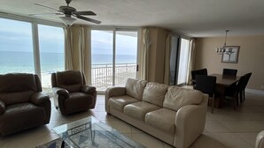 A living room with a sofa, armchairs, a glass coffee table, and a view of the ocean. - SUN, SAND & SURF! (Pensacola)