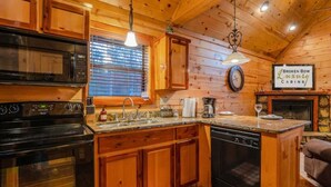 A wooden cabin kitchen with a stove, sink, and a sign reading 'Broken Bow Luxury Cabins'.