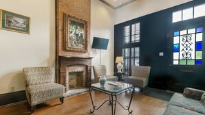 A living room with a fireplace, two armchairs, a sofa, and a glass coffee table.