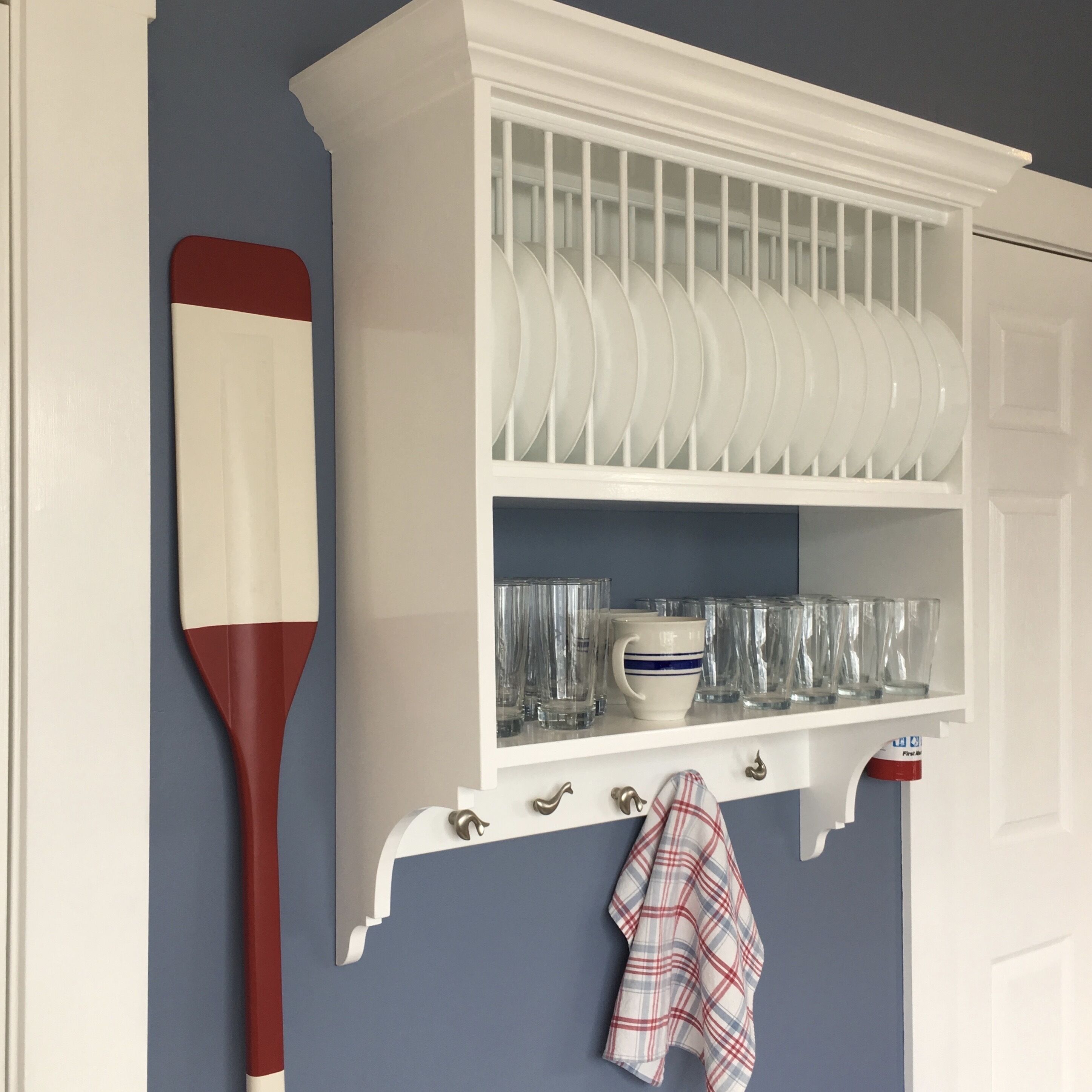 A kitchen with white cabinetry, a dish rack, and a red and white kitchen utensil.