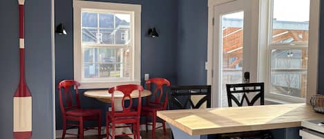 Una cocina con zona de comedor, que incluye una mesa de madera, sillas rojas, una pared de acento azul y una araña.