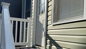 A residential house with a front porch, a set of stairs leading to the entrance, and a door with a window above it.