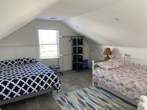 Un dormitorio con dos camas, una ventana, un armario y una lámpara.