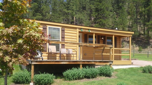 A log cabin with a deck, outdoor seating, and a small garden area.