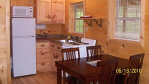 A wooden cabin kitchen with a refrigerator, stove, and wooden cabinets.