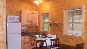 A wooden cabin kitchen with a refrigerator, stove, and wooden cabinets.