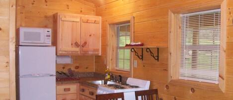 A wooden cabin kitchen with a refrigerator, stove, and wooden cabinets.