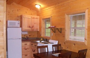 A wooden cabin kitchen with a refrigerator, stove, and wooden cabinets.