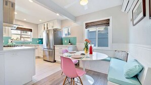 Una cocina moderna con una isla central, armarios blancos y una zona de comedor con una mesa redonda y sillas.