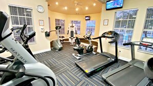 Un gimnasio con cintas de correr, bicicletas estáticas y máquinas de pesas.