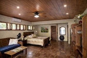 Una habitación acogedora con cama, sofá, techo de madera y estantería.