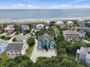 A coastal residential area with houses, a beach, and a clear sky.