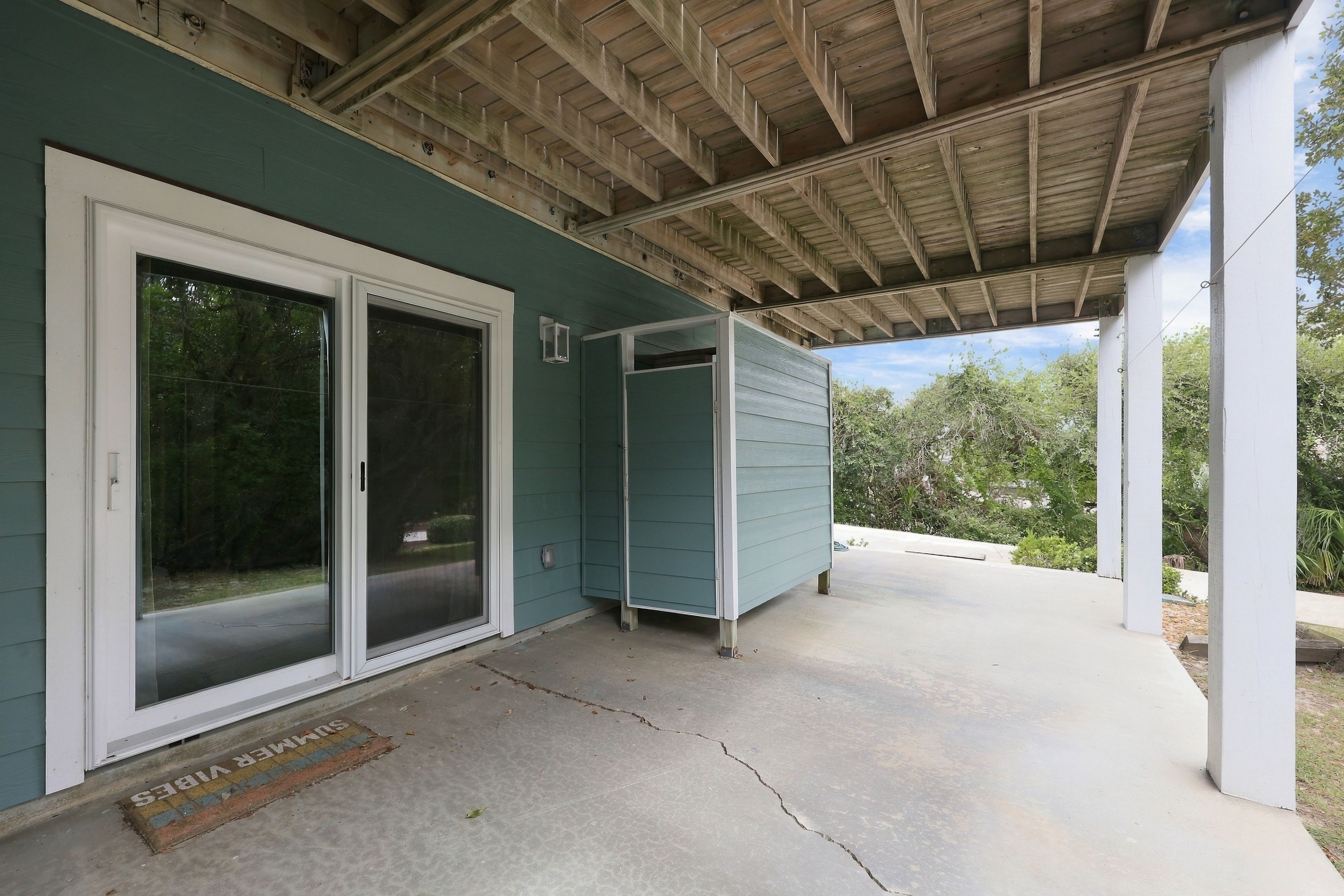 A covered porch with a concrete floor, a sliding glass door, and a small shed.