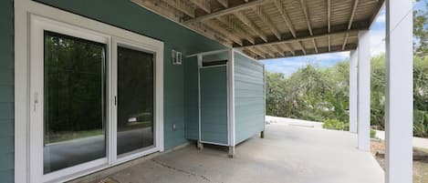 A covered porch with a concrete floor, a sliding glass door, and a small shed.
