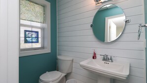 Ein Badezimmer mit Toilette, Waschbecken und Fenster mit Jalousien.
