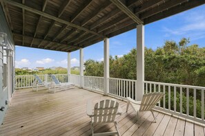 A covered outdoor deck with white railings and two Adirondack chairs. - 2nd Row Duplex with elevator, views, community pool, and direct beach access. (Emerald Isle)