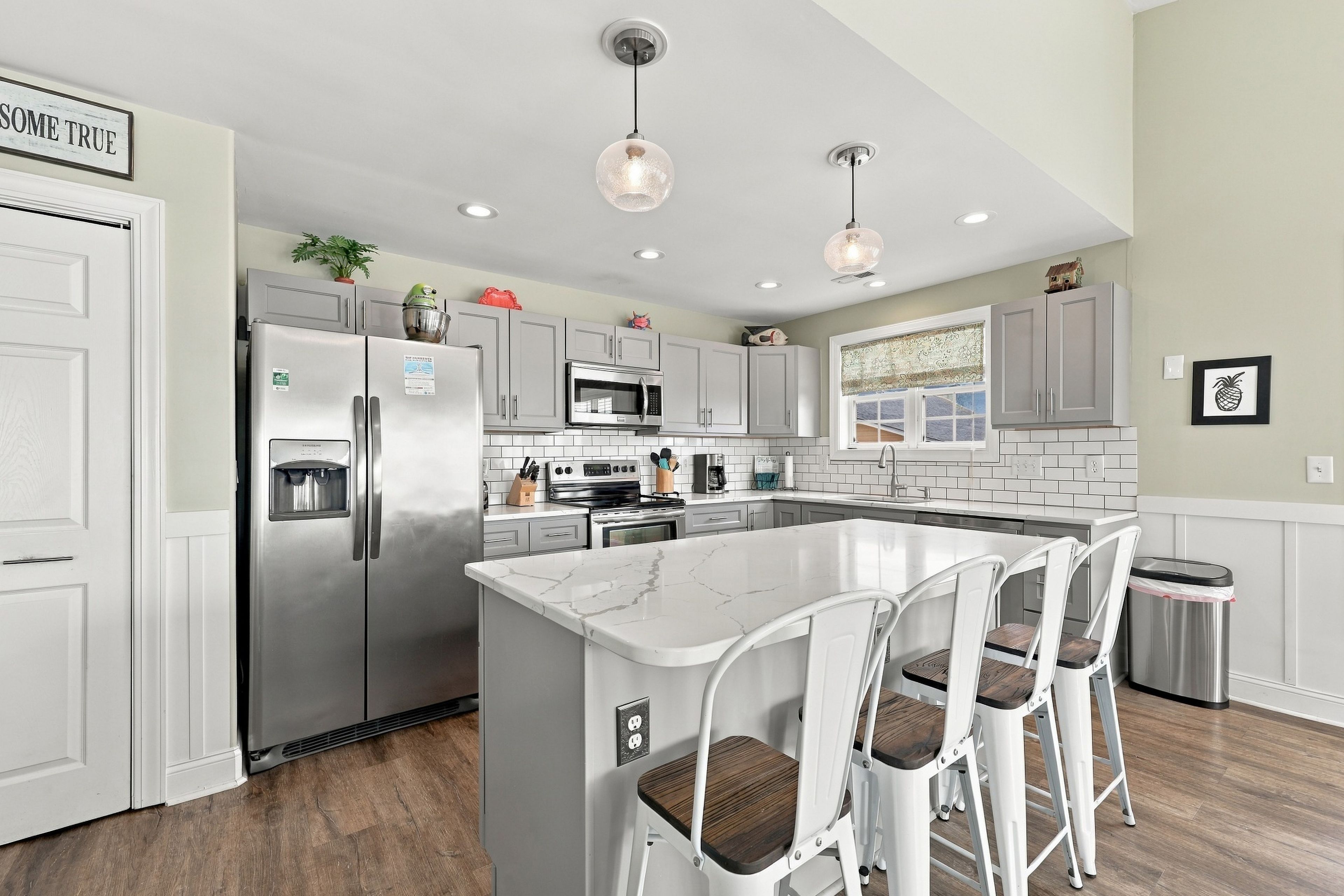 A modern kitchen with a central island, stainless steel appliances, and pendant lighting.