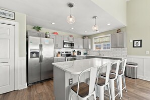 A modern kitchen with a central island, stainless steel appliances, and pendant lighting.