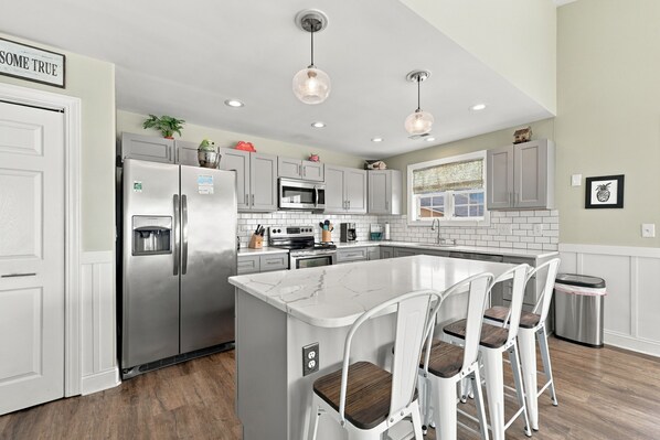A modern kitchen with a central island, stainless steel appliances, and pendant lighting.